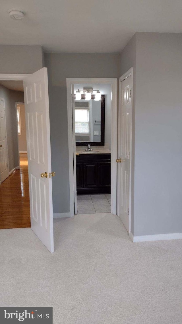 hall with light colored carpet and sink