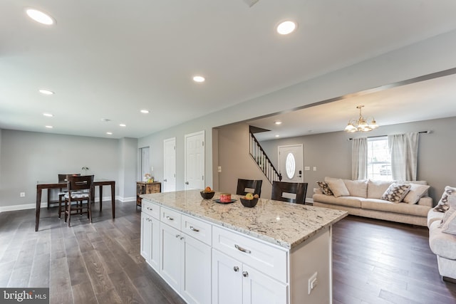 kitchen featuring dark wood-type flooring, decorative light fixtures, a kitchen island, and white cabinets