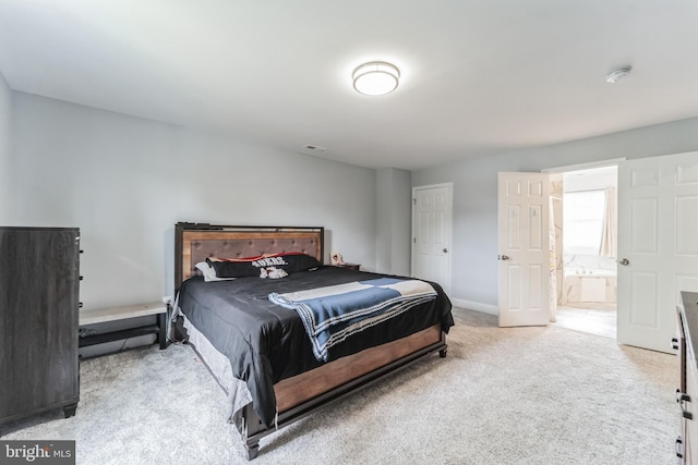 bedroom featuring light carpet and connected bathroom