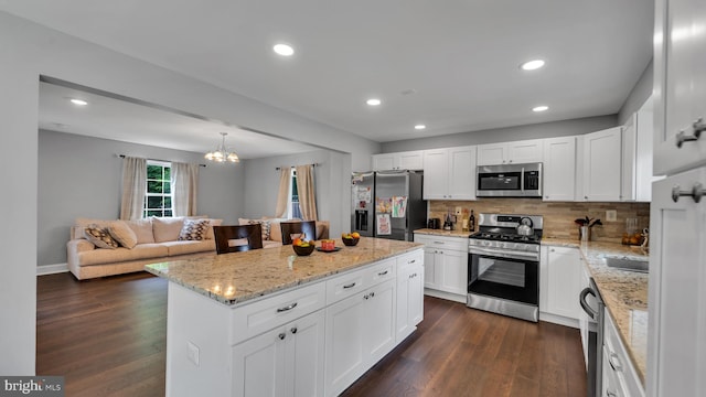 kitchen featuring tasteful backsplash, dark hardwood / wood-style floors, appliances with stainless steel finishes, a center island, and white cabinetry