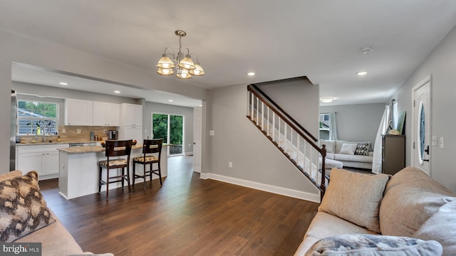 living room with a notable chandelier, sink, and dark hardwood / wood-style flooring