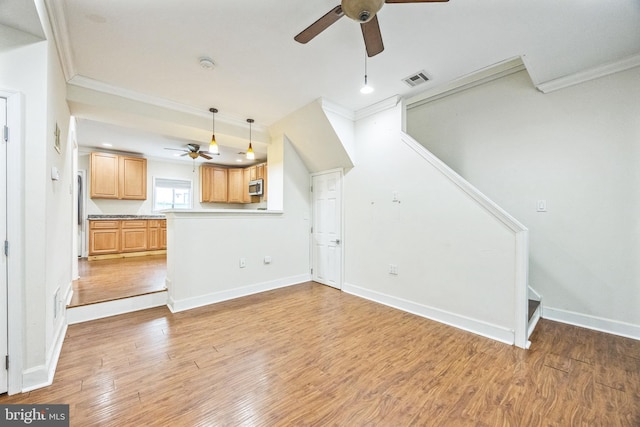 unfurnished living room with ceiling fan, ornamental molding, and light wood-type flooring