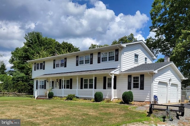 view of front of house featuring covered porch, a garage, and a front lawn