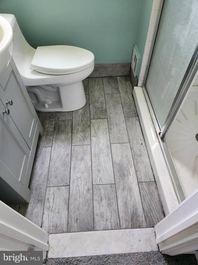 bathroom featuring toilet, an enclosed shower, and hardwood / wood-style flooring