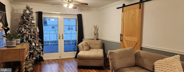 living area featuring french doors, ornamental molding, ceiling fan, a barn door, and dark hardwood / wood-style floors