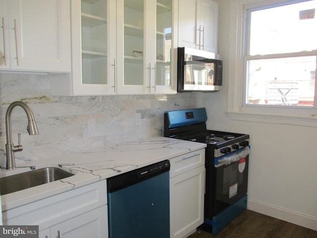 kitchen with stainless steel appliances, white cabinetry, sink, light stone countertops, and dark hardwood / wood-style floors