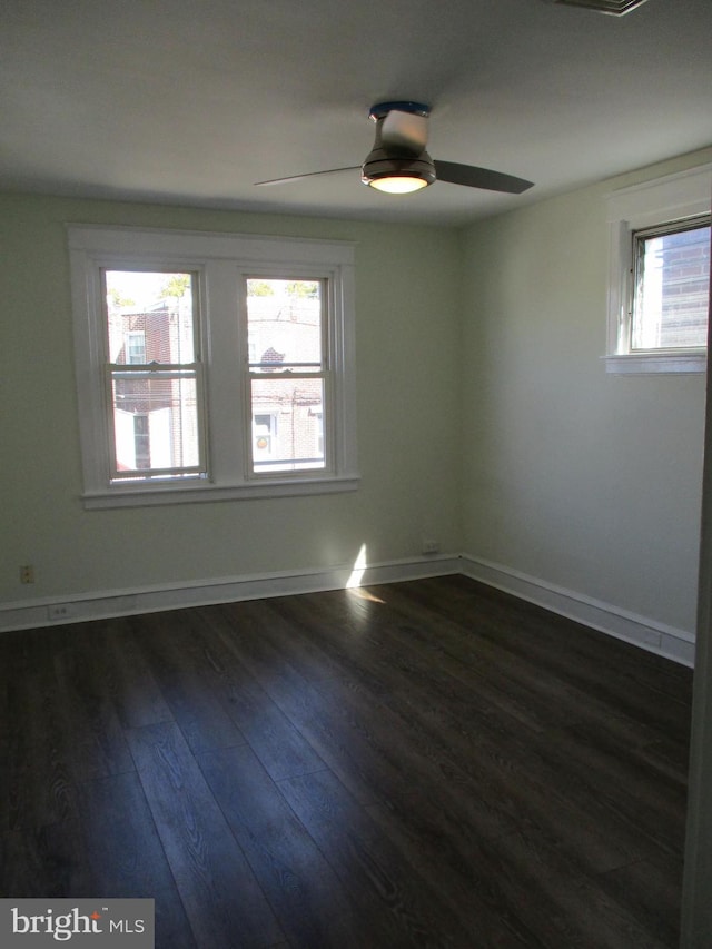 spare room featuring a wealth of natural light, dark wood-type flooring, and ceiling fan