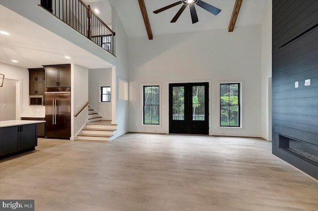 foyer with beam ceiling, high vaulted ceiling, light hardwood / wood-style flooring, and a healthy amount of sunlight