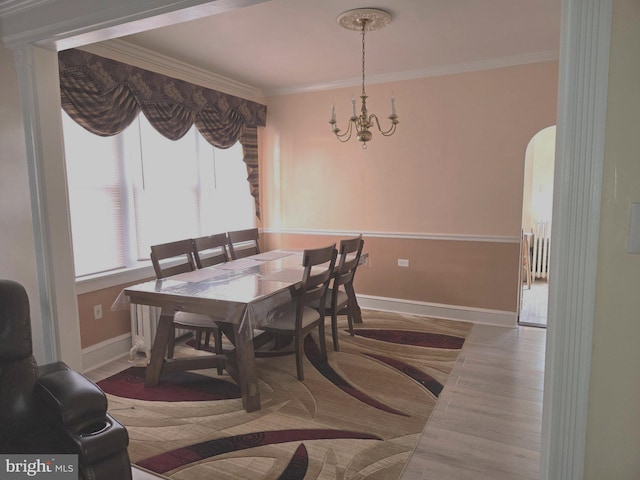 dining area featuring an inviting chandelier, arched walkways, baseboards, and crown molding