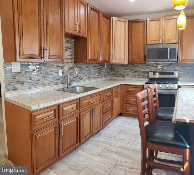 kitchen featuring a kitchen breakfast bar, decorative light fixtures, sink, backsplash, and appliances with stainless steel finishes