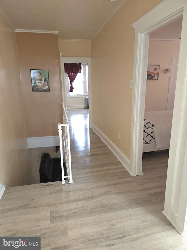 hallway with crown molding, baseboards, an upstairs landing, and wood finished floors