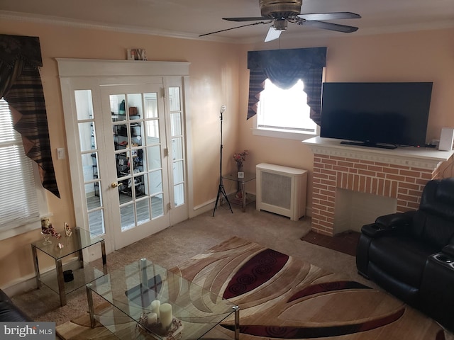 living room featuring a brick fireplace, ceiling fan, crown molding, radiator, and light colored carpet