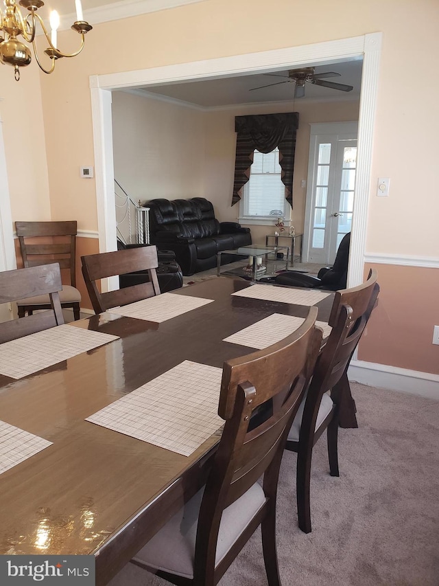 dining area with ceiling fan with notable chandelier, crown molding, and carpet flooring