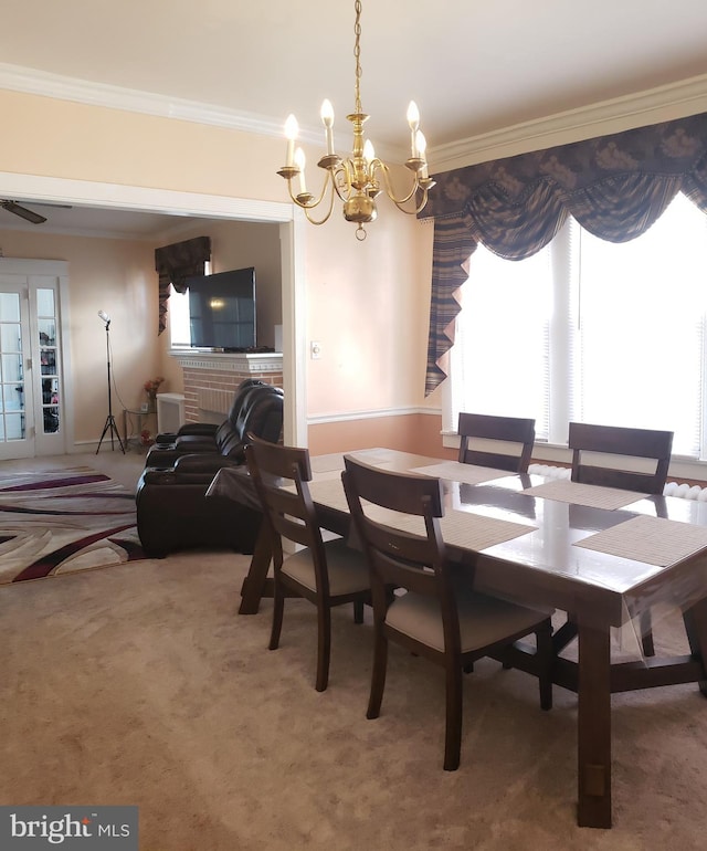 dining room with a brick fireplace, a notable chandelier, crown molding, and carpet