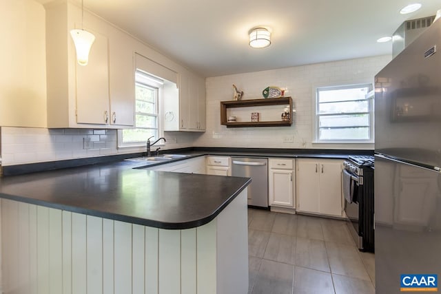 kitchen featuring tasteful backsplash, sink, kitchen peninsula, white cabinets, and appliances with stainless steel finishes