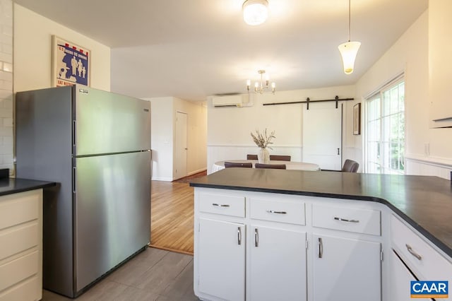 kitchen featuring a barn door, a wall mounted air conditioner, stainless steel refrigerator, and white cabinetry