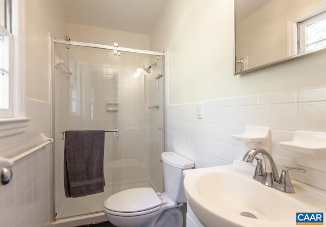 bathroom with sink, tile walls, toilet, and a shower with door