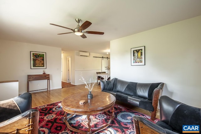 living room with light wood-type flooring, ceiling fan, a barn door, and a wall mounted AC