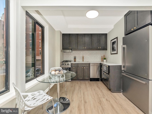 kitchen with appliances with stainless steel finishes, light countertops, dark brown cabinetry, and a sink