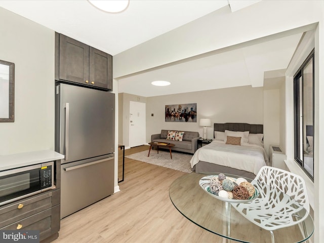 bedroom with light hardwood / wood-style floors and stainless steel fridge