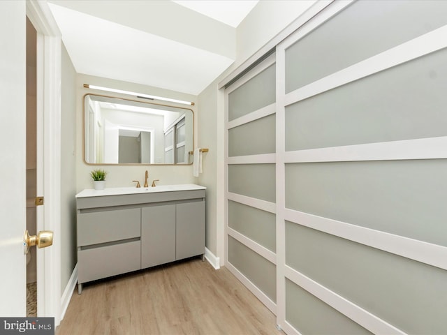 bathroom with wood finished floors, vanity, and baseboards