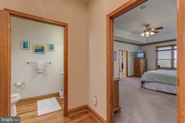 interior space with ensuite bath, light hardwood / wood-style flooring, and ceiling fan