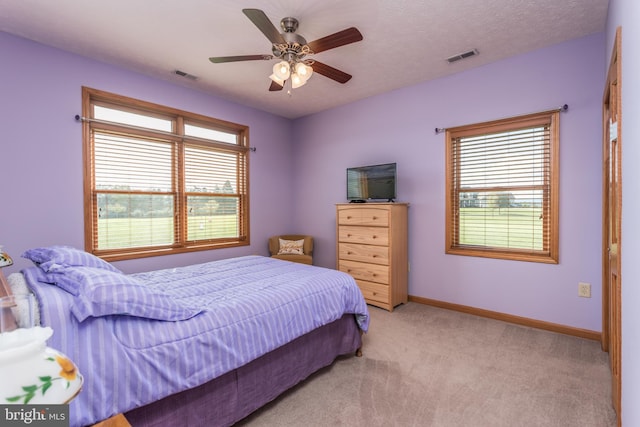 carpeted bedroom with ceiling fan, a textured ceiling, and multiple windows