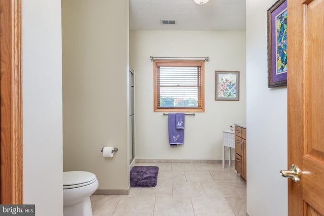 bathroom with a shower with door, a textured ceiling, toilet, vanity, and tile patterned floors