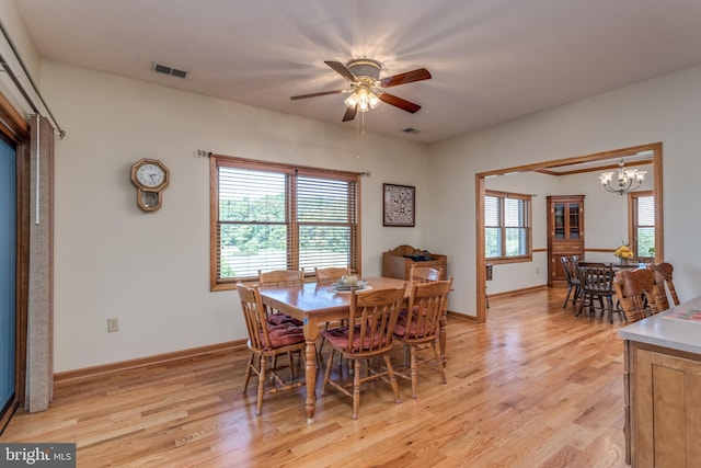 dining area with a wealth of natural light, light wood-type flooring, and ceiling fan with notable chandelier