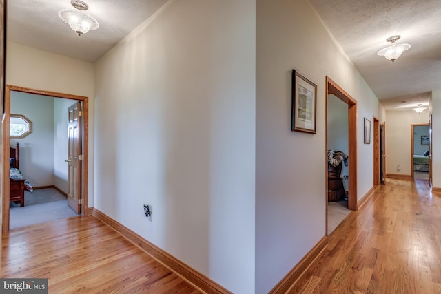 corridor featuring a textured ceiling and light wood-type flooring