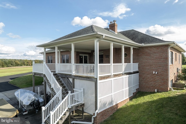 rear view of house with covered porch and a lawn