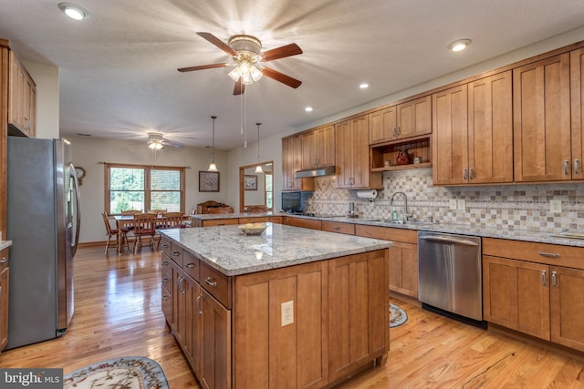 kitchen featuring appliances with stainless steel finishes, a kitchen island, hanging light fixtures, and light hardwood / wood-style floors