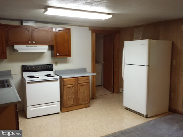 kitchen featuring wood walls, white appliances, sink, washer / dryer, and a textured ceiling