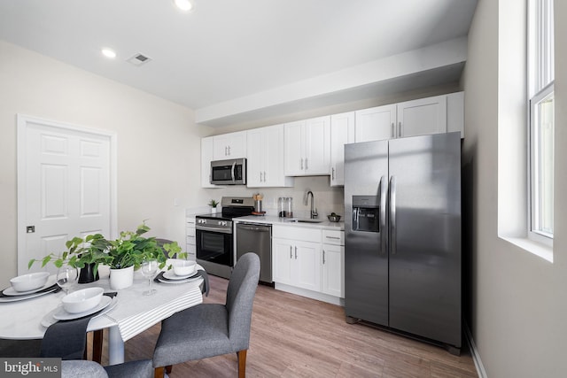 kitchen with light hardwood / wood-style floors, sink, stainless steel appliances, and white cabinets