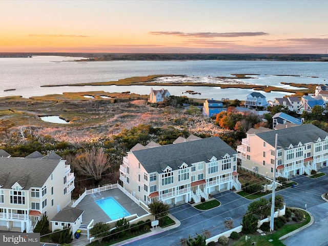 aerial view at dusk featuring a water view