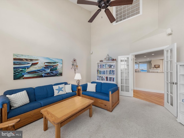 carpeted living room featuring french doors, ceiling fan, and a high ceiling