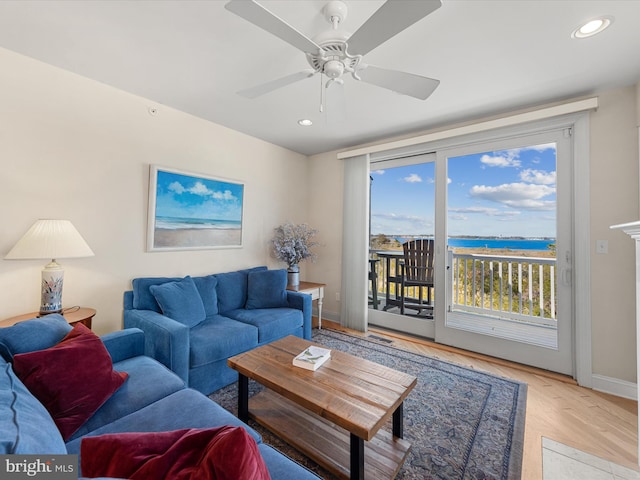 living room featuring a water view, light hardwood / wood-style floors, and ceiling fan