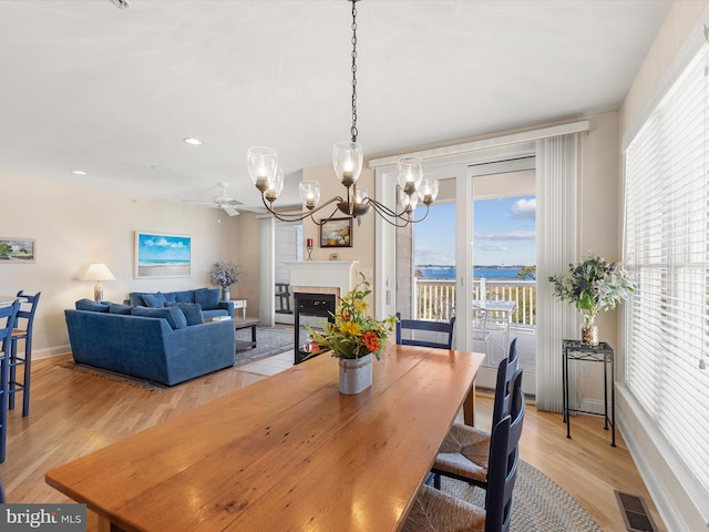 dining room with light wood-type flooring and ceiling fan with notable chandelier