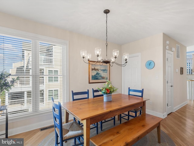 dining area with a wealth of natural light, an inviting chandelier, and light wood-type flooring