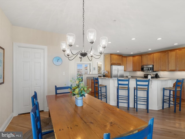 dining space with light hardwood / wood-style floors and a chandelier