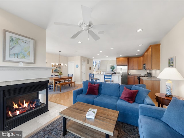 living room with a multi sided fireplace, light hardwood / wood-style flooring, and ceiling fan with notable chandelier