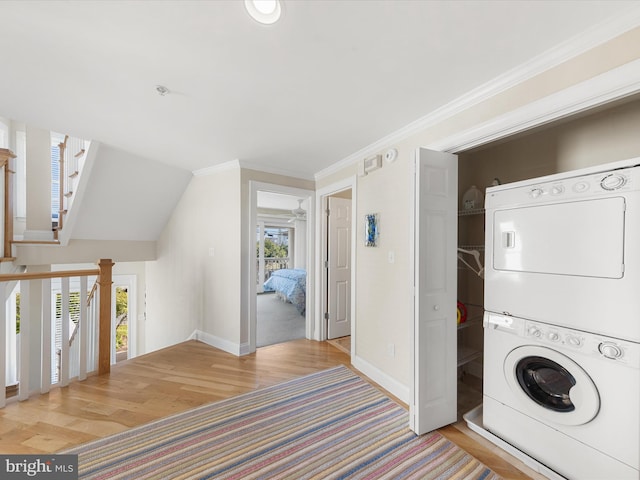 washroom with stacked washer / drying machine, crown molding, a wealth of natural light, and light hardwood / wood-style floors