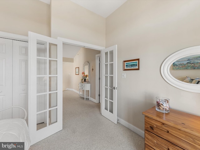 corridor featuring french doors, light colored carpet, and vaulted ceiling