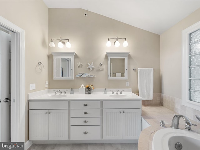 bathroom featuring vanity, tiled bath, and lofted ceiling