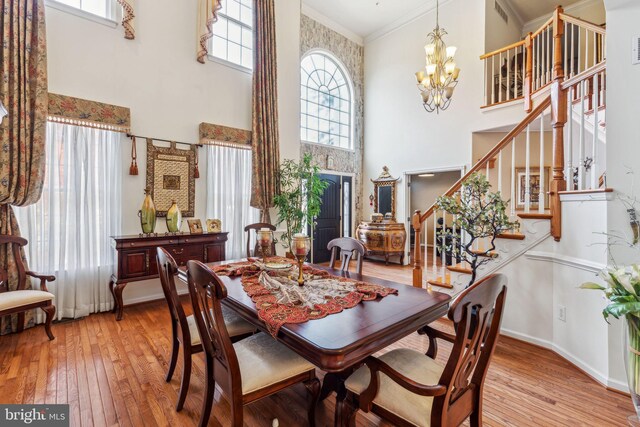 dining space with crown molding, a healthy amount of sunlight, light hardwood / wood-style flooring, and a high ceiling