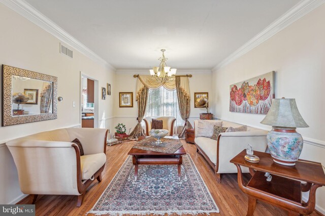 living room with ornamental molding, a chandelier, and light hardwood / wood-style floors