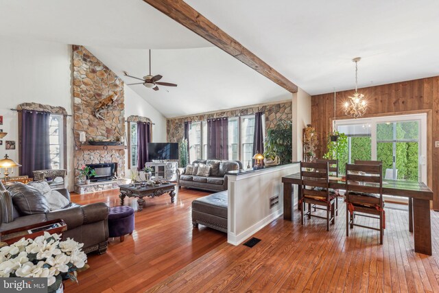 living room featuring a stone fireplace, hardwood / wood-style flooring, ceiling fan with notable chandelier, and a wealth of natural light