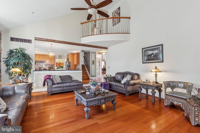 living room featuring high vaulted ceiling, light wood-type flooring, and ceiling fan with notable chandelier