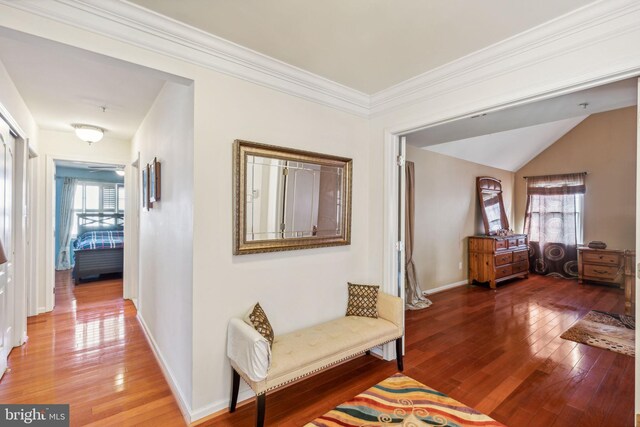 hallway with ornamental molding, hardwood / wood-style flooring, and lofted ceiling