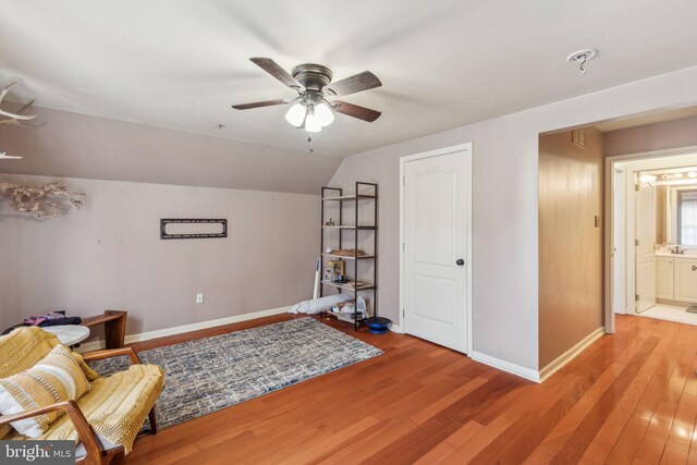 living area with lofted ceiling, hardwood / wood-style floors, sink, and ceiling fan